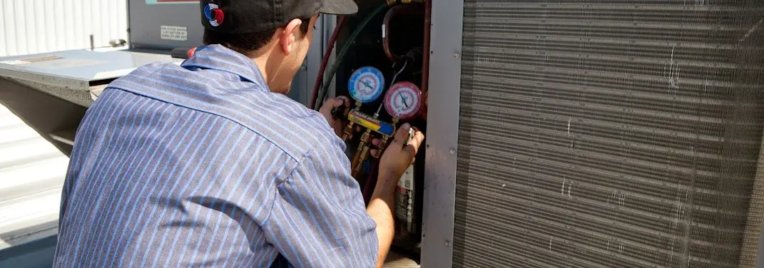 HVAC technician servicing a condenser unit in Corinth